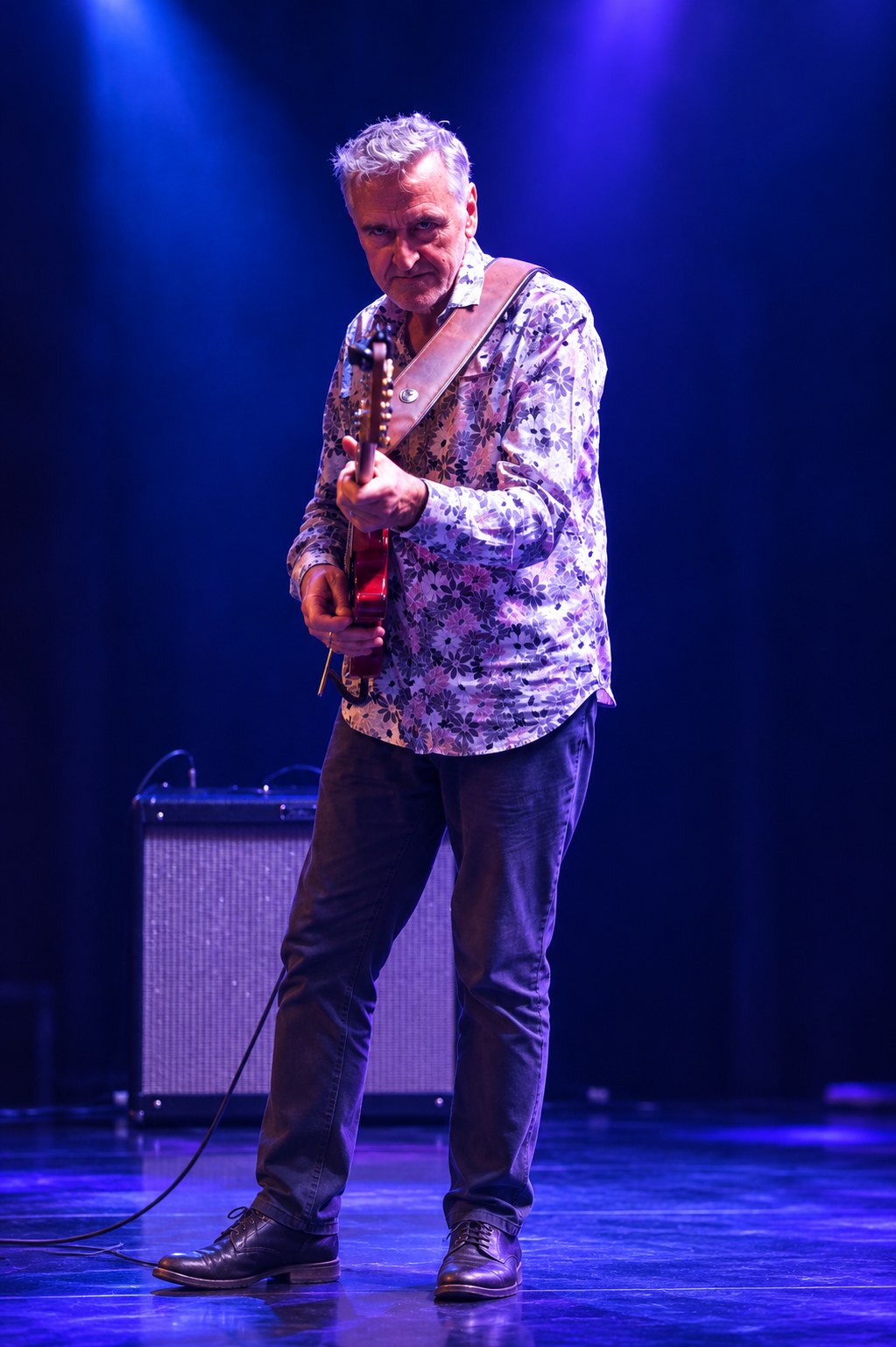Sunday Service guitarist playing beneath blue stage lights.