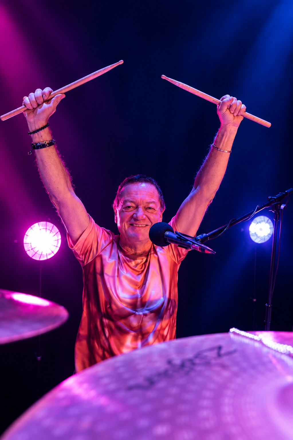 Sunday Service drummer raising both drumsticks during a live performance.
