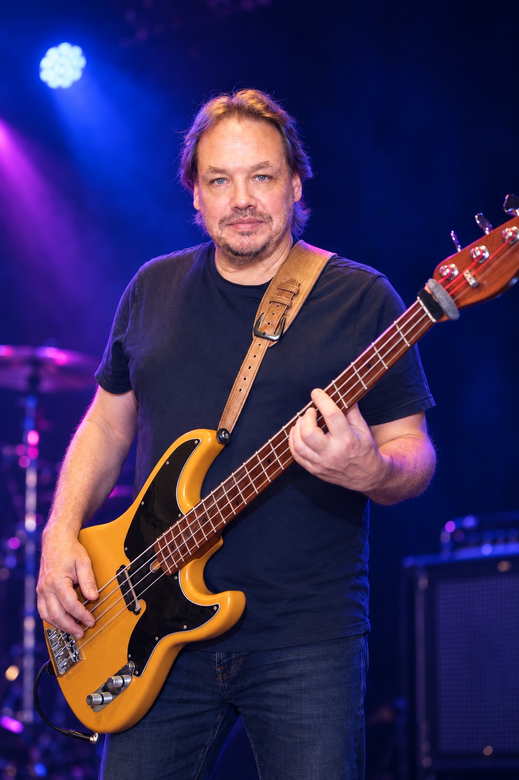 Sunday Service bassist playing his amber bass under blue and violet stage lights.
